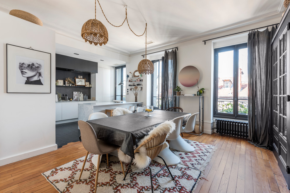 Inspiration pour une salle à manger ouverte sur la cuisine bohème avec un mur blanc, un sol en bois brun et aucune cheminée.