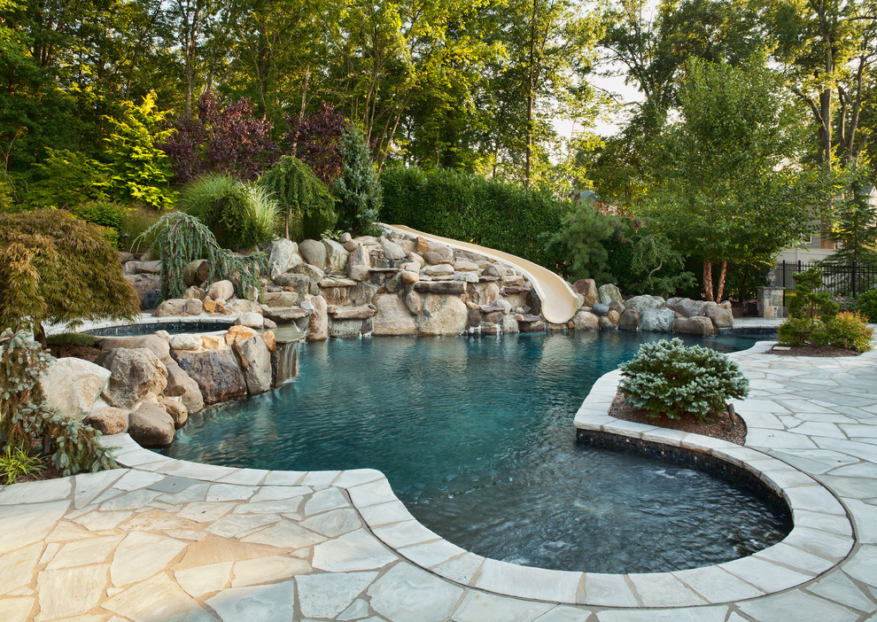Expansive mediterranean backyard custom-shaped natural pool in New York with a hot tub and natural stone pavers.