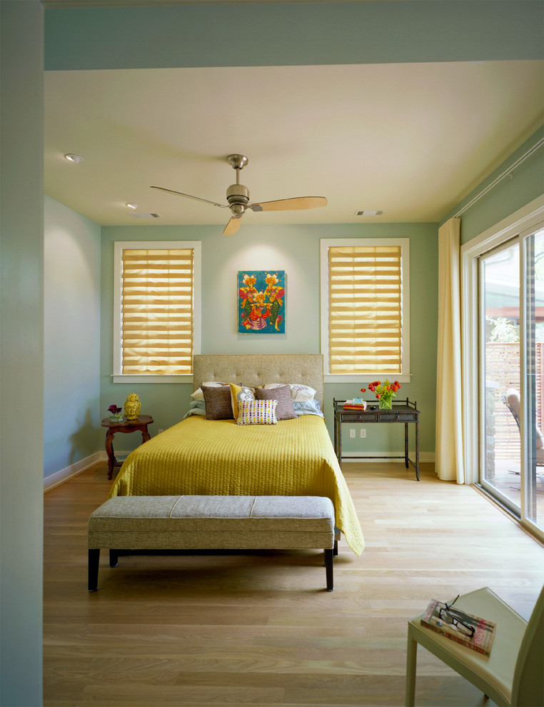 This is an example of a contemporary bedroom in Austin with green walls and light hardwood floors.