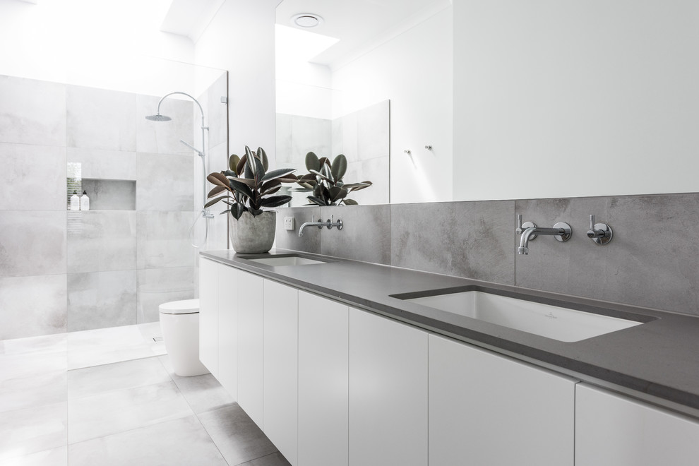 This is an example of a large contemporary bathroom in Melbourne with white cabinets, an open shower, a one-piece toilet, gray tile, porcelain tile, white walls, porcelain floors, an undermount sink, engineered quartz benchtops, grey floor and an open shower.