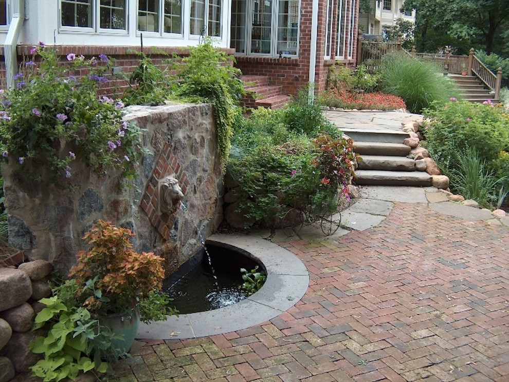Design ideas for a large traditional backyard patio in Milwaukee with a water feature, brick pavers and a pergola.