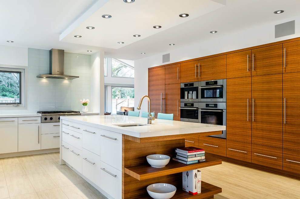 This is an example of a contemporary kitchen in Vancouver with an undermount sink, flat-panel cabinets, medium wood cabinets, white splashback, glass tile splashback and stainless steel appliances.