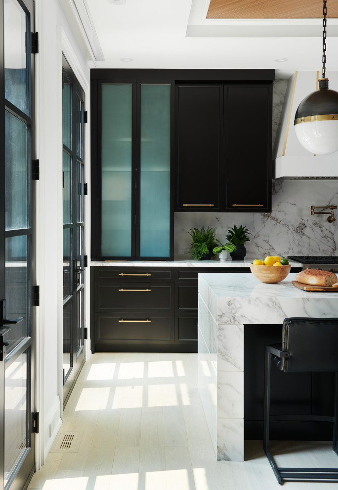 Large contemporary l-shaped open plan kitchen in Toronto with a double-bowl sink, shaker cabinets, black cabinets, marble benchtops, white splashback, marble splashback, panelled appliances, light hardwood floors, with island, white benchtop and recessed.