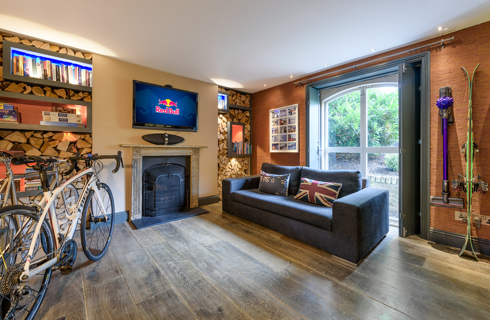 This is an example of a mid-sized transitional enclosed family room in London with multi-coloured walls, dark hardwood floors, a wall-mounted tv, brown floor and a standard fireplace.