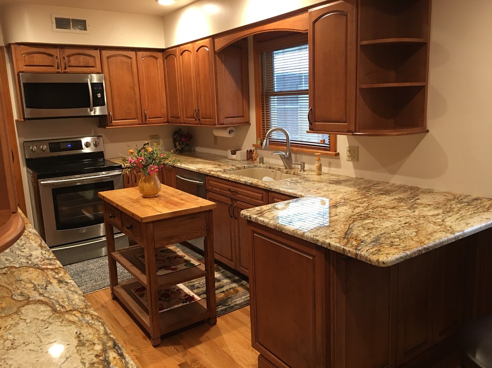 Inspiration for a mid-sized timeless l-shaped ceramic tile and beige floor open concept kitchen remodel with an undermount sink, raised-panel cabinets, light wood cabinets, solid surface countertops, stainless steel appliances and an island
