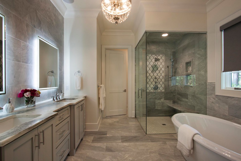 This is an example of a large transitional master bathroom in Other with shaker cabinets, grey cabinets, a freestanding tub, gray tile, marble, marble floors, marble benchtops, grey floor, a hinged shower door, grey walls, a two-piece toilet, an undermount sink and a curbless shower.