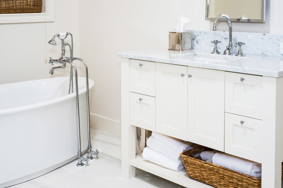 Freestanding bathtub - large transitional master white tile and subway tile marble floor and white floor freestanding bathtub idea with shaker cabinets, white cabinets, white walls, an undermount sink, marble countertops, a hinged shower door and white countertops