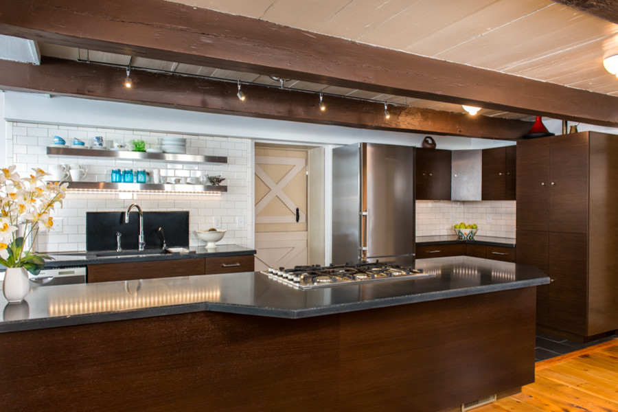 Large transitional galley open concept kitchen photo in Boston with an undermount sink, flat-panel cabinets, dark wood cabinets, concrete countertops, white backsplash, subway tile backsplash, stainless steel appliances, white walls and an island