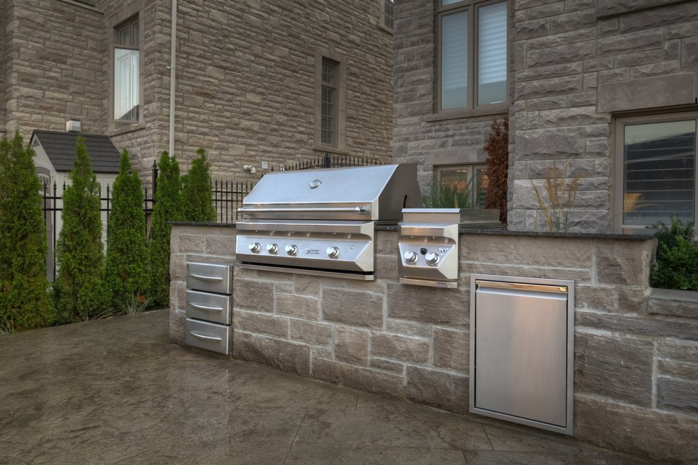Design ideas for a mid-sized contemporary backyard patio in Toronto with an outdoor kitchen, natural stone pavers and no cover.