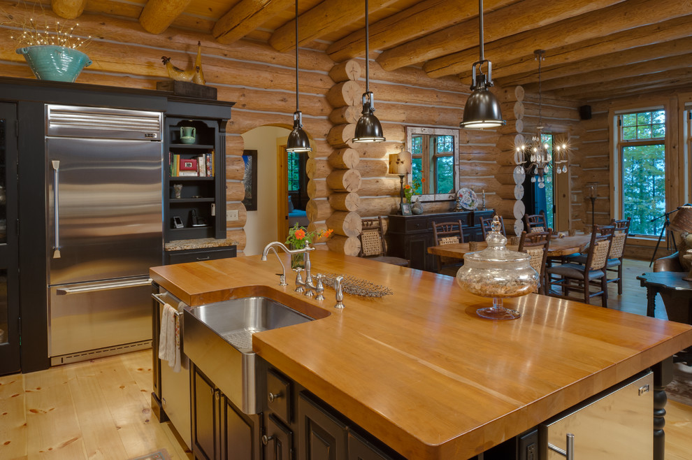 Mountain style l-shaped eat-in kitchen photo with an undermount sink, raised-panel cabinets, black cabinets, wood countertops, multicolored backsplash, stone slab backsplash and stainless steel appliances