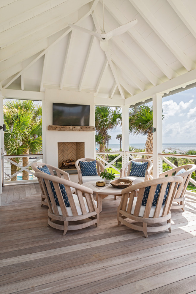 Inspiration for an expansive beach style backyard verandah in Charleston with with fireplace, decking, a roof extension and cable railing.