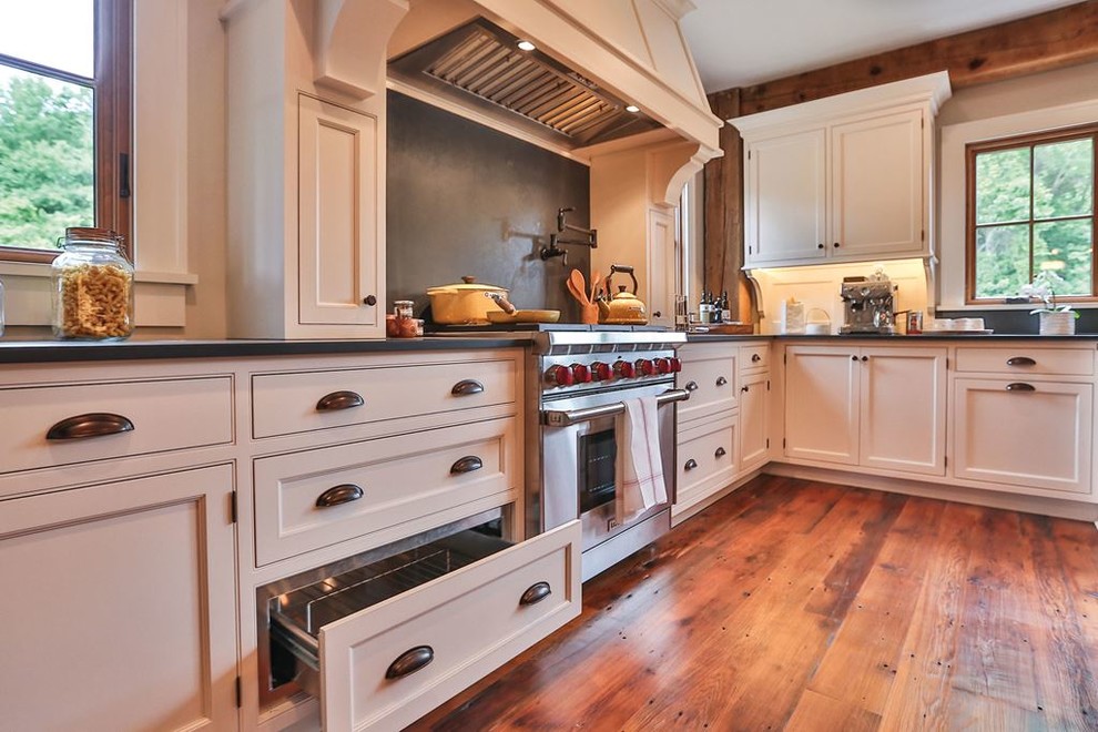 Example of a mid-sized transitional u-shaped medium tone wood floor eat-in kitchen design in Denver with a farmhouse sink, shaker cabinets, white cabinets, concrete countertops, black backsplash, cement tile backsplash, black appliances and an island