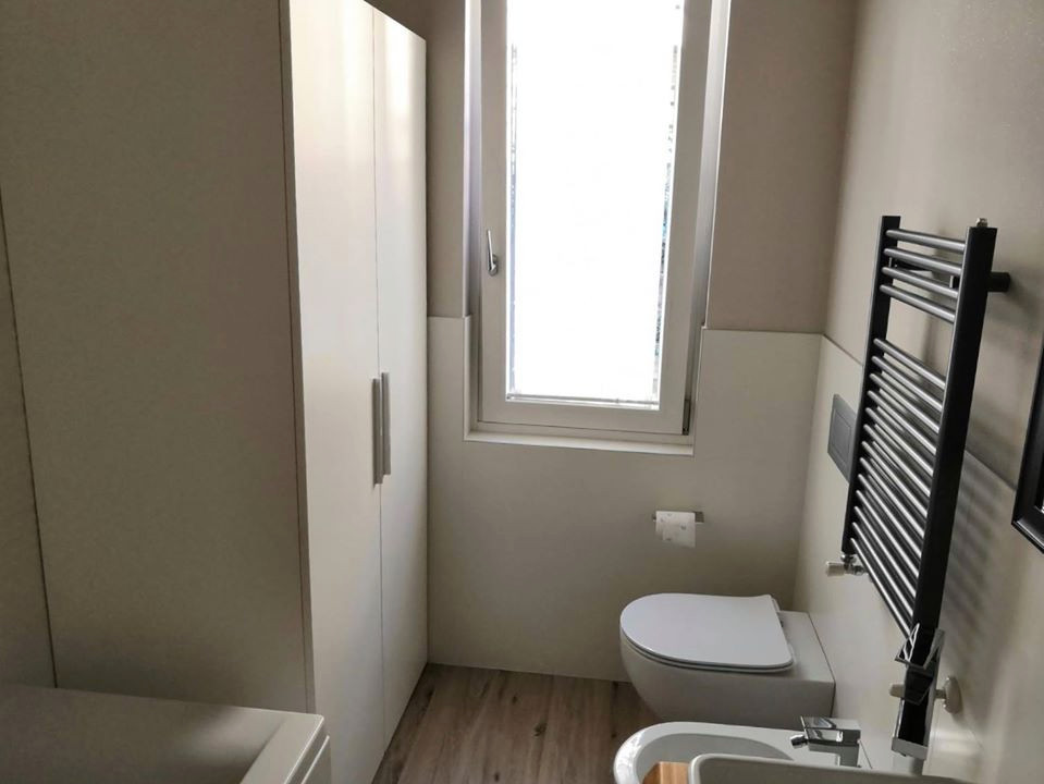 Design ideas for a small contemporary master bathroom in Milan with open cabinets, brown cabinets, a corner tub, a two-piece toilet, white tile, wood-look tile, white walls, porcelain floors, a vessel sink, wood benchtops, a laundry, a single vanity and a floating vanity.