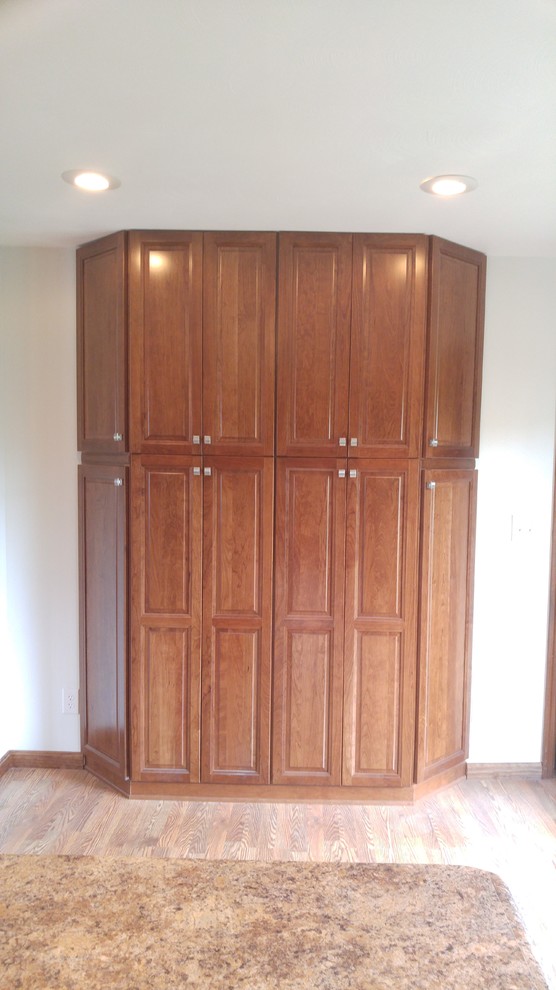 Large country kitchen pantry in Indianapolis with raised-panel cabinets, medium wood cabinets and medium hardwood floors.