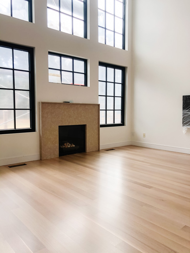Nordisches Wohnzimmer mit weißer Wandfarbe, hellem Holzboden, Kamin, Kaminumrandung aus Stein, beigem Boden und gewölbter Decke in Vancouver