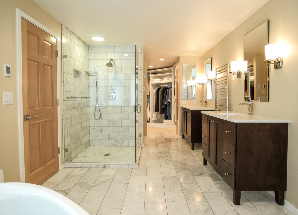 Mid-sized contemporary master bathroom in Seattle with recessed-panel cabinets, dark wood cabinets, a drop-in tub, a corner shower, a two-piece toilet, gray tile, marble, beige walls, marble floors, an undermount sink, solid surface benchtops, grey floor, a hinged shower door and white benchtops.