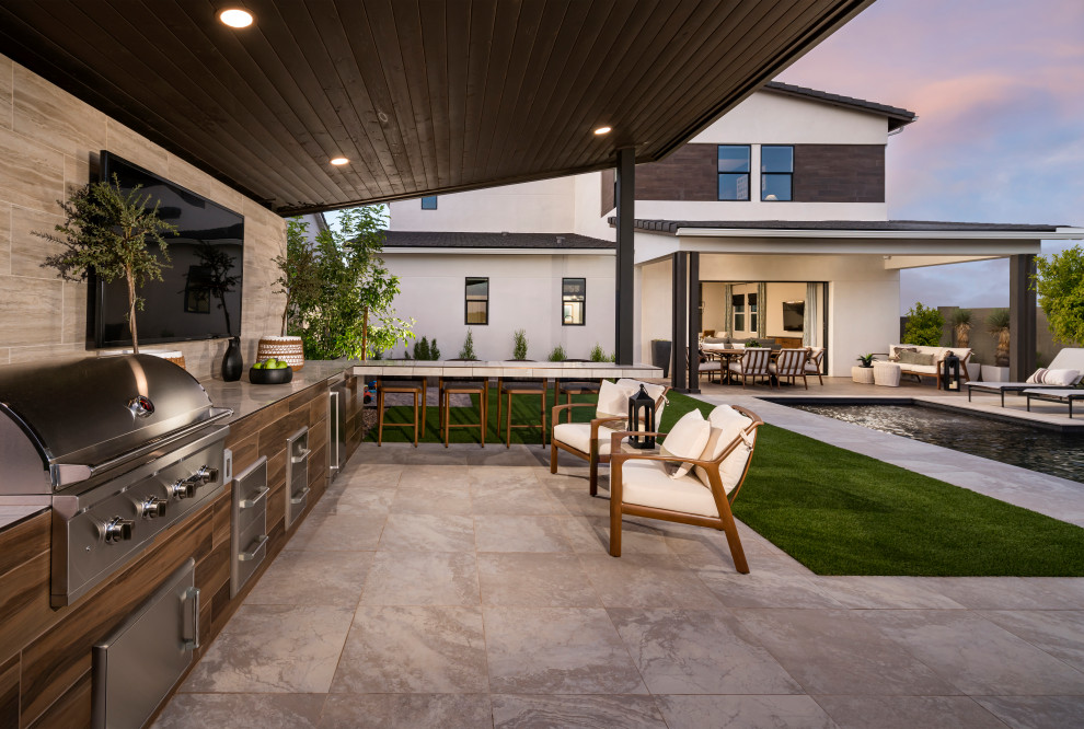 Immagine di un grande patio o portico moderno dietro casa con graniglia di granito e un parasole