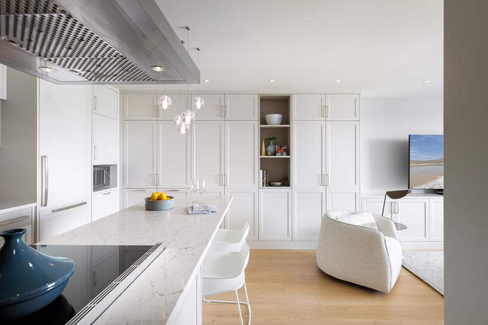 Example of a small transitional brown floor kitchen design in Vancouver with a drop-in sink, shaker cabinets, white cabinets, white backsplash, stainless steel appliances, an island and white countertops