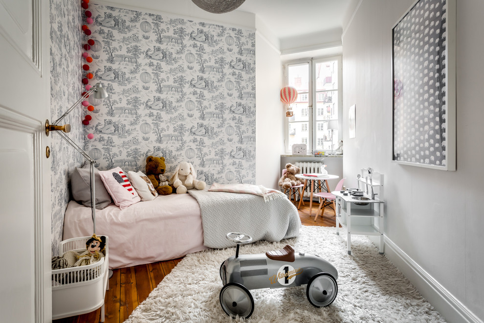 Design ideas for a scandinavian kids' bedroom for kids 4-10 years old and girls in Stockholm with multi-coloured walls, medium hardwood floors and brown floor.