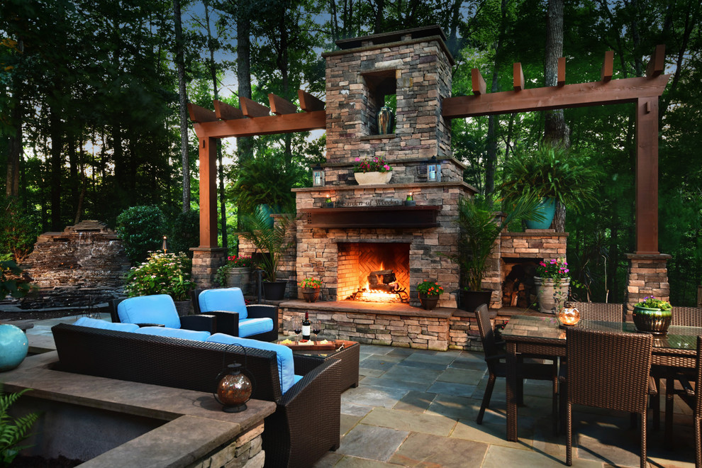 This is an example of a large country backyard patio in Other with with fireplace, tile and no cover.