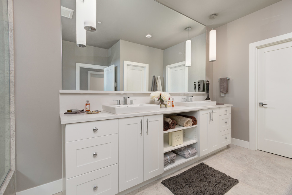 Photo of a mid-sized transitional master bathroom in Seattle with shaker cabinets, white cabinets, an alcove shower, beige tile, stone tile, beige walls, porcelain floors, a drop-in sink, solid surface benchtops, beige floor and a hinged shower door.