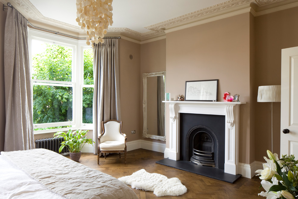 Inspiration for a mid-sized traditional bedroom in London with dark hardwood floors, a standard fireplace and brown floor.