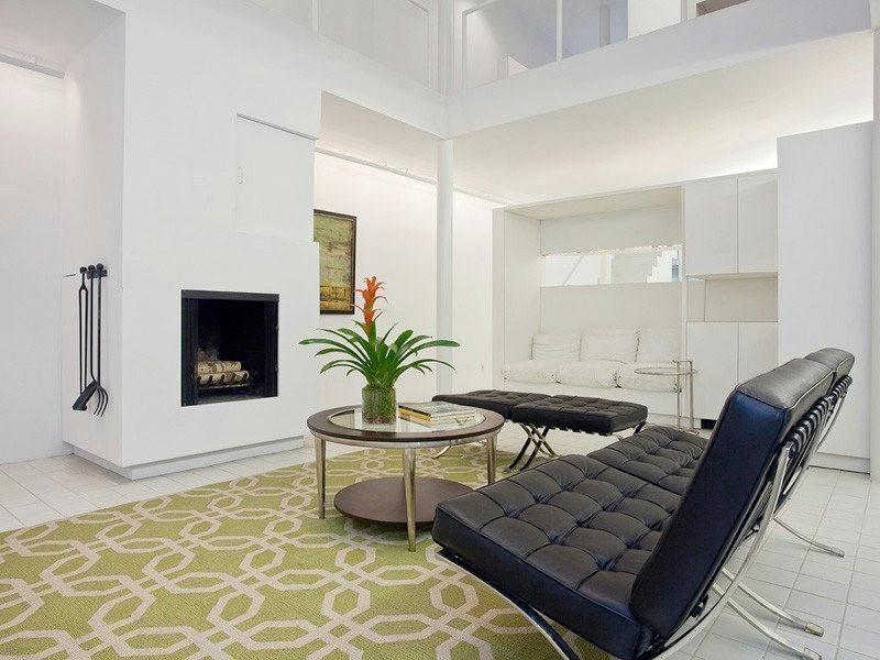 This is an example of a mid-sized modern loft-style living room in New York with white walls, ceramic floors, a standard fireplace and a stone fireplace surround.