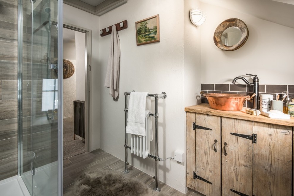 This is an example of a mid-sized country kids bathroom in Cornwall with shaker cabinets, light wood cabinets, a curbless shower, a one-piece toilet, gray tile, slate, white walls, light hardwood floors, a trough sink and wood benchtops.