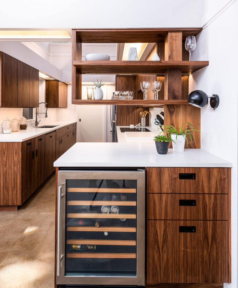 Photo of a mid-sized modern galley kitchen in Other with an undermount sink, flat-panel cabinets, brown cabinets, stainless steel appliances, white splashback and white benchtop.