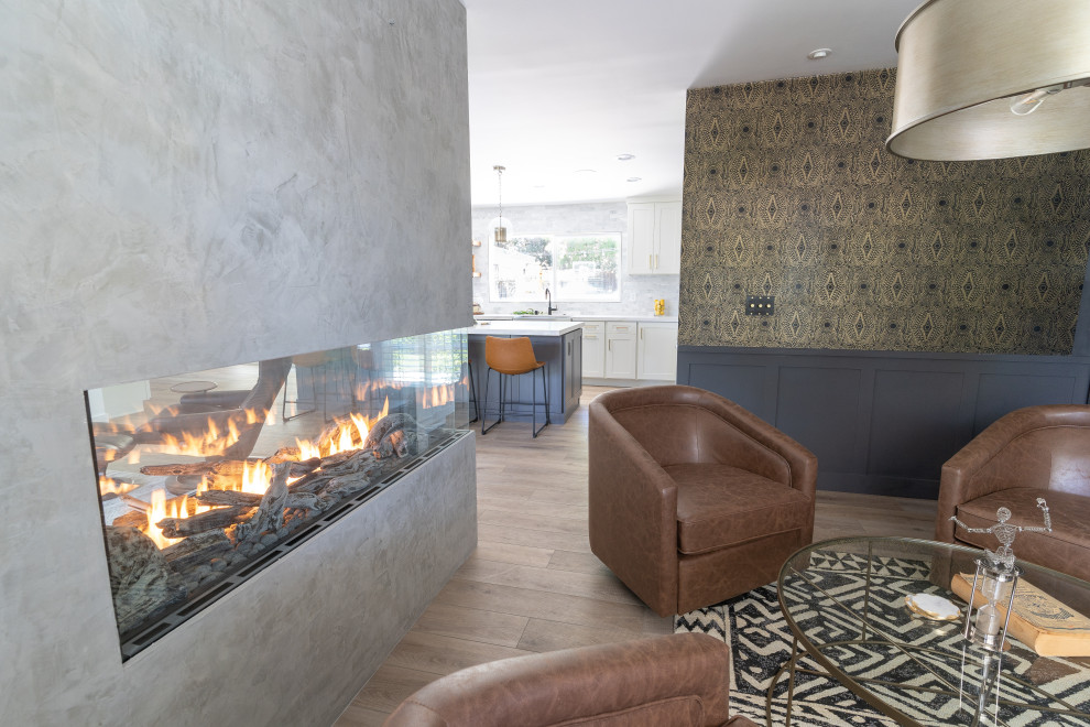 Inspiration for a mid-sized transitional living room in Orange County with blue walls, vinyl floors, a corner fireplace, a concrete fireplace surround, brown floor and wallpaper.