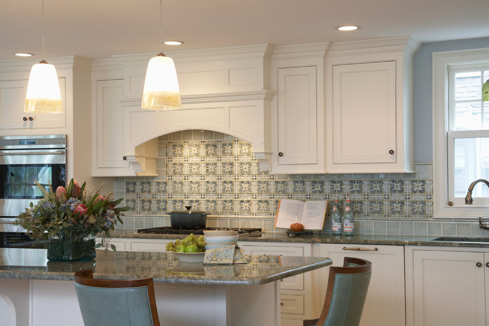 This is an example of a transitional kitchen in Boston with beaded inset cabinets, white cabinets, granite benchtops, blue splashback and stainless steel appliances.