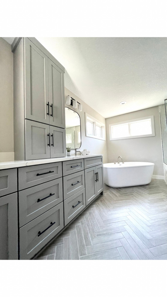This is an example of a mid-sized transitional master bathroom in Minneapolis with shaker cabinets, grey cabinets, a freestanding tub, grey walls, wood-look tile, an undermount sink, engineered quartz benchtops, grey floor, white benchtops, a double vanity and a built-in vanity.