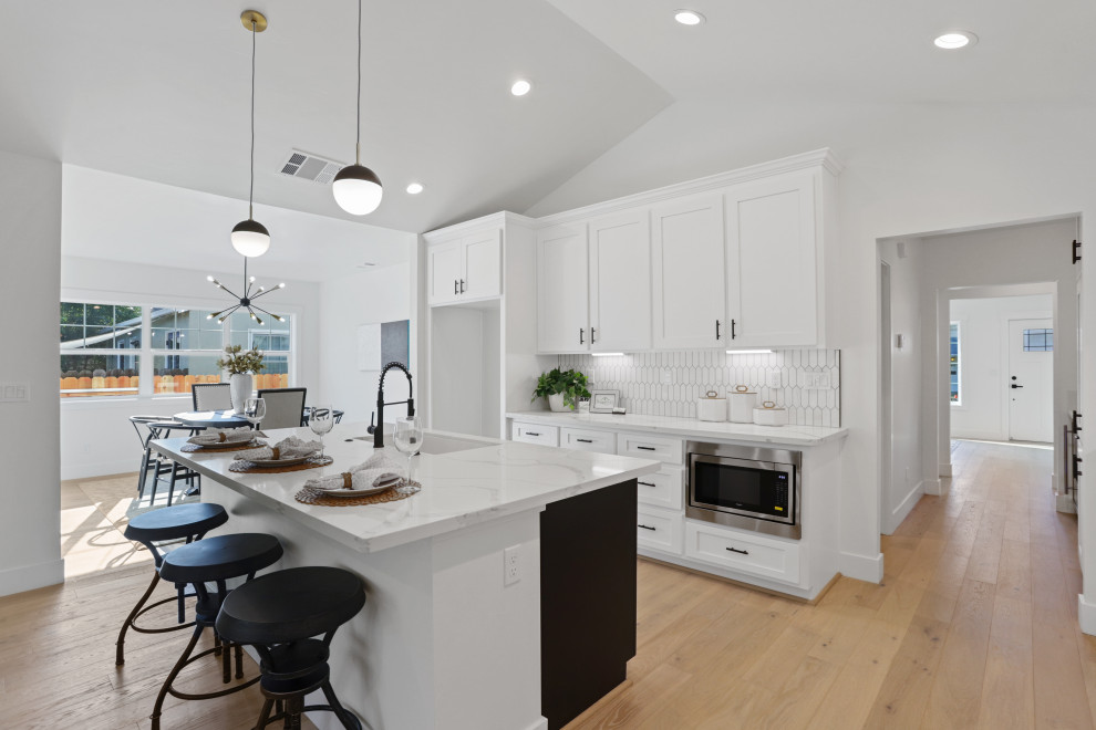 Inspiration for a mid-sized country l-shaped open plan kitchen in Sacramento with an undermount sink, shaker cabinets, white cabinets, quartz benchtops, white splashback, mosaic tile splashback, stainless steel appliances, light hardwood floors, with island, white floor, white benchtop and vaulted.