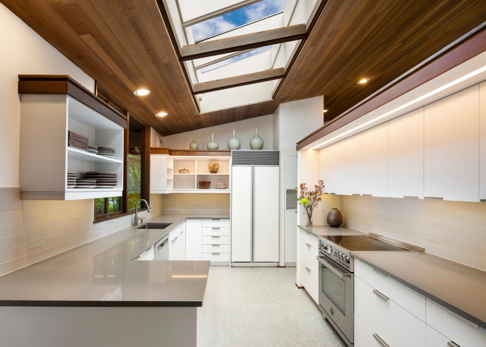 Inspiration for a mid-sized midcentury u-shaped eat-in kitchen in Seattle with a single-bowl sink, flat-panel cabinets, white cabinets, quartz benchtops, grey splashback, ceramic splashback, stainless steel appliances, porcelain floors, no island, grey floor and grey benchtop.