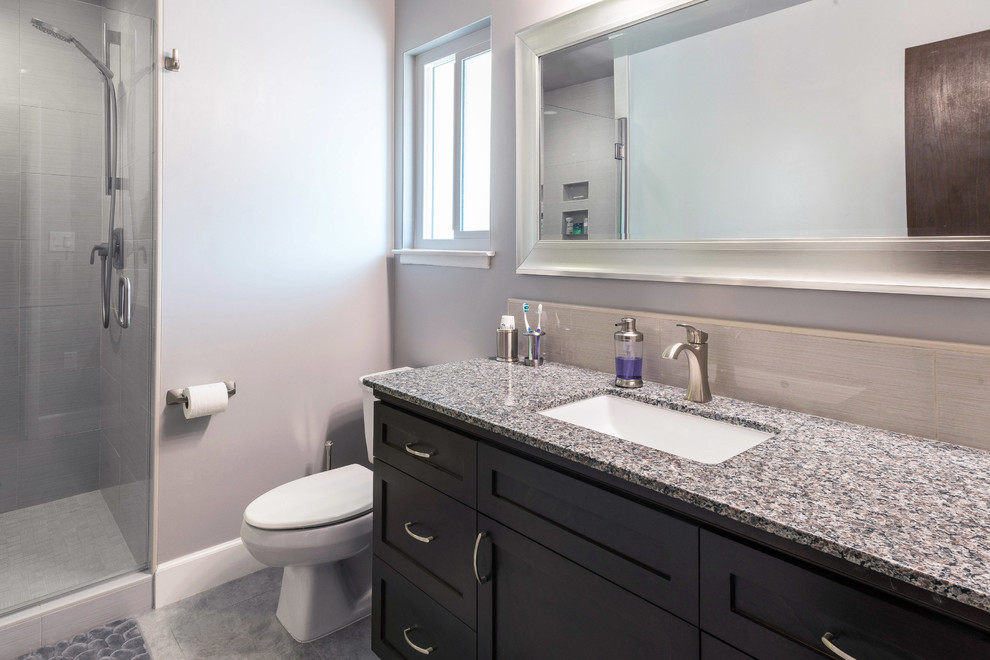 Example of a large transitional master gray tile and subway tile alcove shower design with shaker cabinets, dark wood cabinets, a two-piece toilet, blue walls, an undermount sink and granite countertops