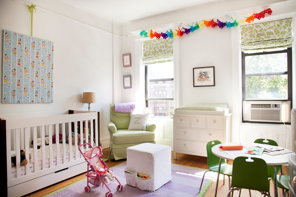 Large transitional nursery in New York with white walls and medium hardwood floors for girls.