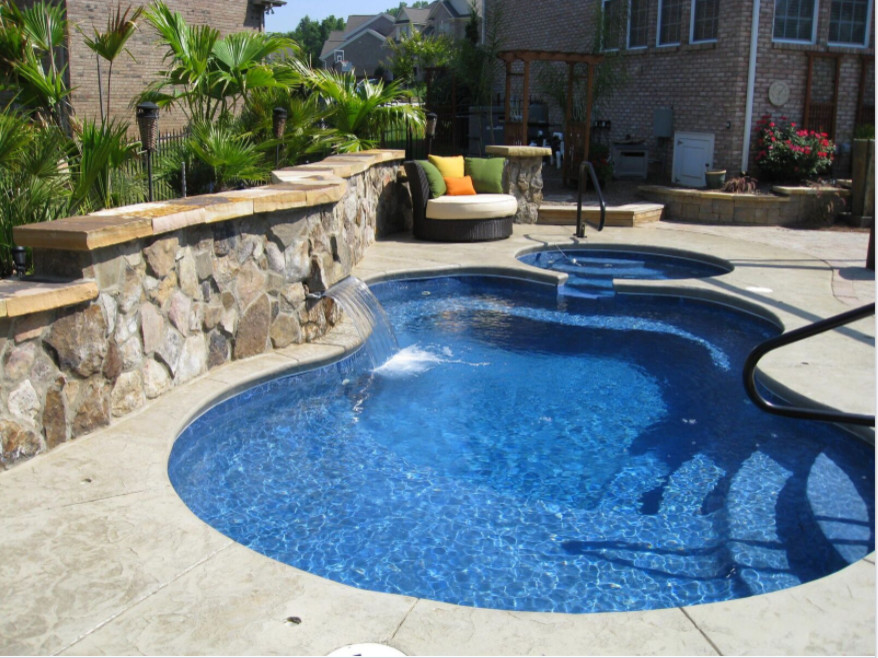 Inspiration for a mid-sized tropical backyard custom-shaped pool in Charlotte with a hot tub and brick pavers.