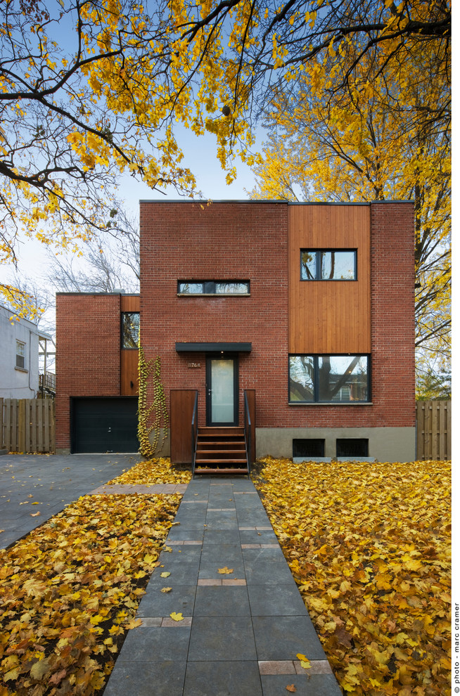 Design ideas for a contemporary split-level red exterior in Montreal with mixed siding and a flat roof.