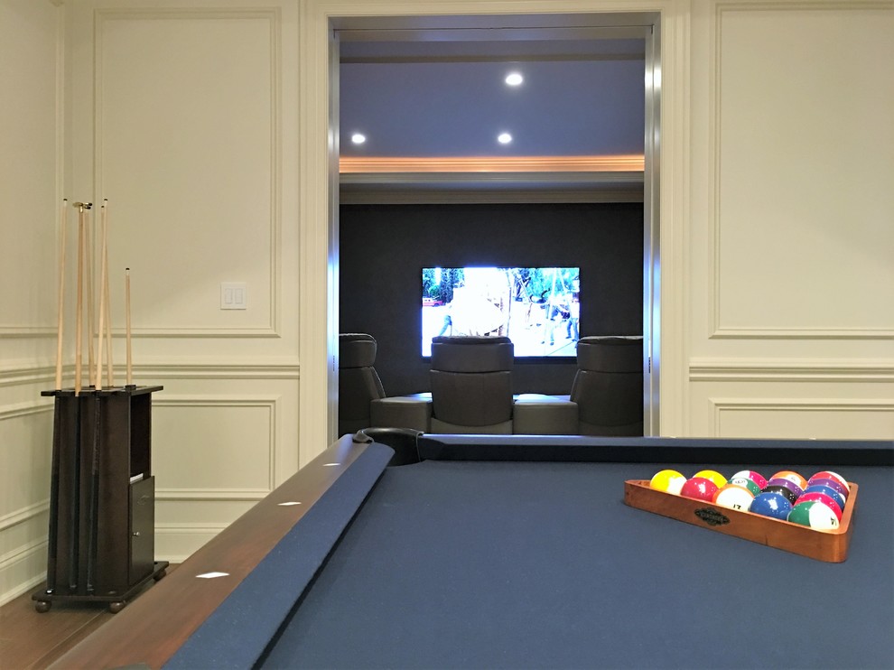 Photo of a large transitional enclosed home theatre in New York with medium hardwood floors, a wall-mounted tv, brown floor and grey walls.