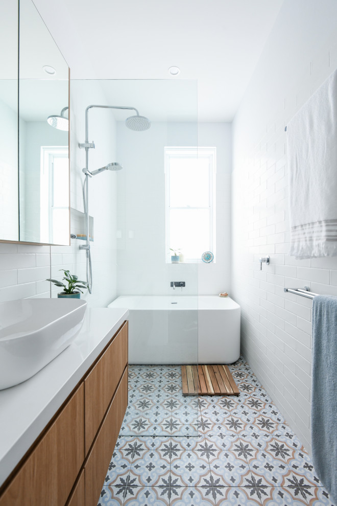 This is an example of a mid-sized modern 3/4 wet room bathroom in Sydney with flat-panel cabinets, medium wood cabinets, a freestanding tub, white tile, ceramic tile, white walls, ceramic floors, a drop-in sink, engineered quartz benchtops, blue floor, an open shower, white benchtops, a single vanity and a floating vanity.