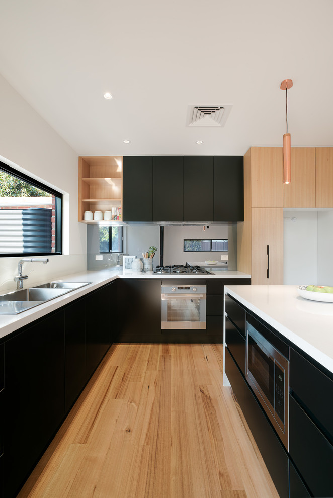 Design ideas for a mid-sized contemporary galley eat-in kitchen in Melbourne with a double-bowl sink, flat-panel cabinets, black cabinets, quartz benchtops, metallic splashback, glass sheet splashback, stainless steel appliances, light hardwood floors and with island.