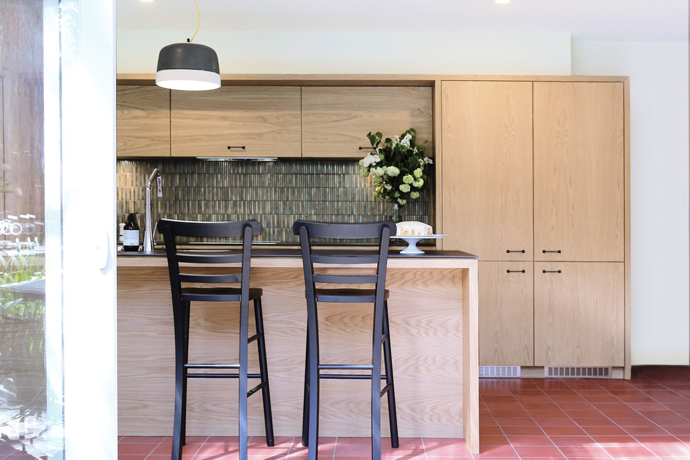 Design ideas for a mid-sized modern u-shaped eat-in kitchen in Melbourne with an undermount sink, flat-panel cabinets, light wood cabinets, solid surface benchtops, multi-coloured splashback, mosaic tile splashback, stainless steel appliances, with island and terra-cotta floors.