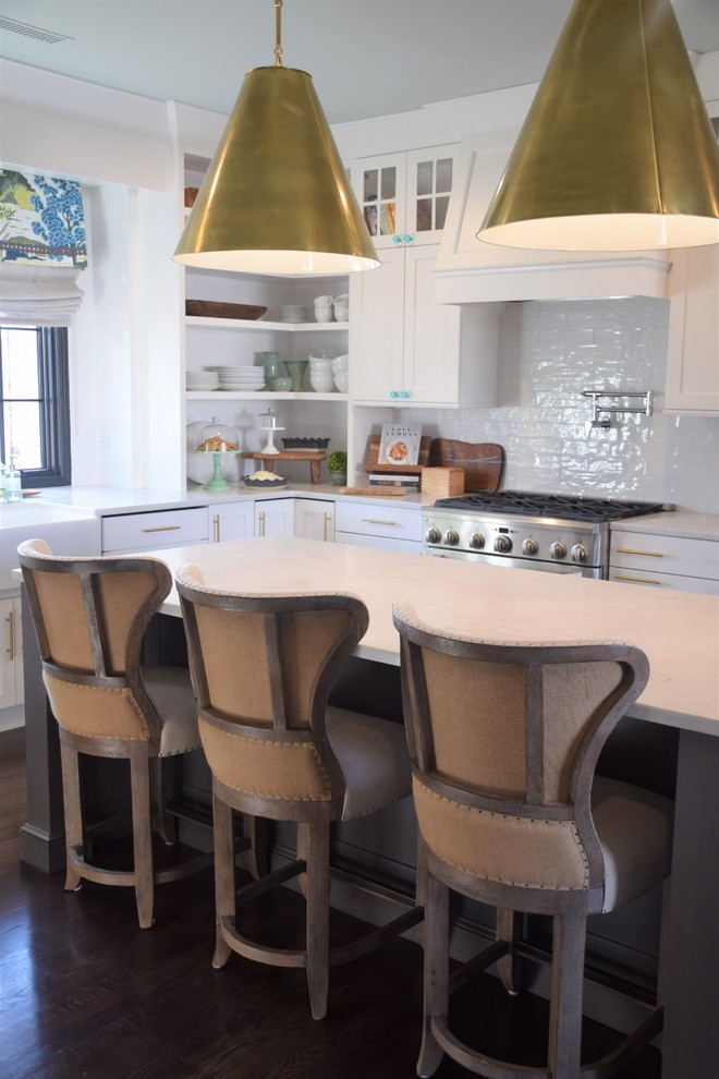 Inspiration for a large transitional dark wood floor eat-in kitchen remodel with a farmhouse sink, shaker cabinets, white cabinets, quartzite countertops, white backsplash, subway tile backsplash, stainless steel appliances and an island