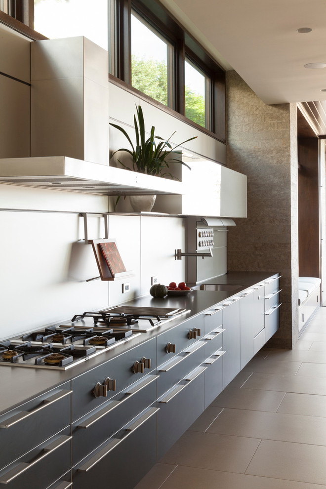 Design ideas for a large contemporary single-wall eat-in kitchen in Los Angeles with flat-panel cabinets, grey cabinets, an undermount sink, stainless steel benchtops, metallic splashback, metal splashback, panelled appliances, porcelain floors and grey floor.
