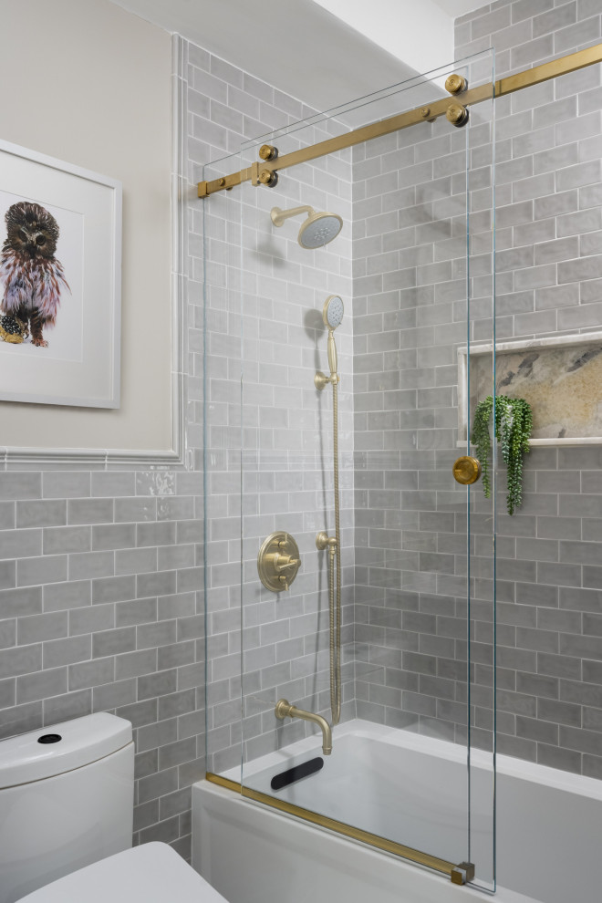 This is an example of a mid-sized transitional kids bathroom in Boston with beaded inset cabinets, grey cabinets, a drop-in tub, a shower/bathtub combo, a bidet, gray tile, subway tile, beige walls, marble floors, an undermount sink, quartzite benchtops, grey floor, a sliding shower screen, grey benchtops, a niche, a single vanity, a freestanding vanity and recessed.