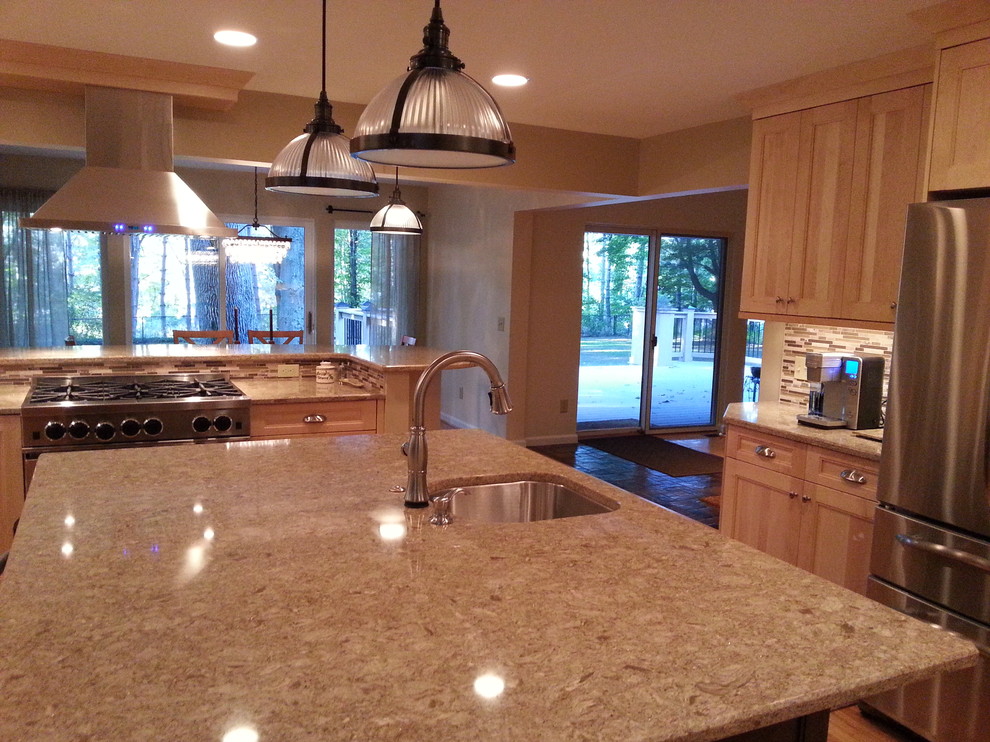 Mid-sized transitional l-shaped medium tone wood floor kitchen pantry photo in New York with an undermount sink, raised-panel cabinets, light wood cabinets, beige backsplash, stone slab backsplash, stainless steel appliances and an island