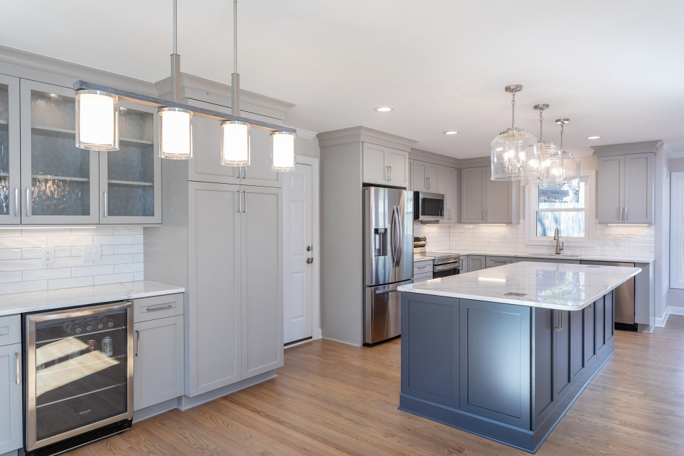 Example of a mid-sized transitional l-shaped medium tone wood floor and brown floor eat-in kitchen design in Raleigh with an undermount sink, shaker cabinets, gray cabinets, quartz countertops, white backsplash, subway tile backsplash, stainless steel appliances, an island and white countertops