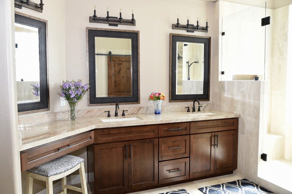 Mid-sized contemporary master bathroom in Phoenix with shaker cabinets, brown cabinets, beige tile, porcelain tile, beige walls, travertine floors, an undermount sink, granite benchtops, beige floor, a hinged shower door, beige benchtops, a shower seat, a double vanity and a built-in vanity.