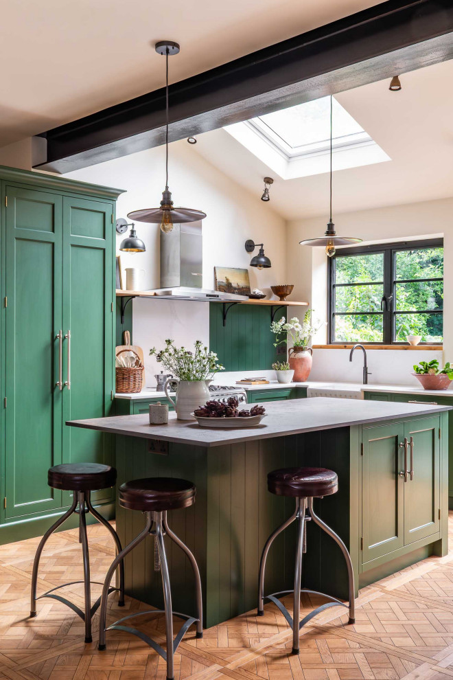 Photo of a traditional kitchen with green cabinets and light hardwood flooring.