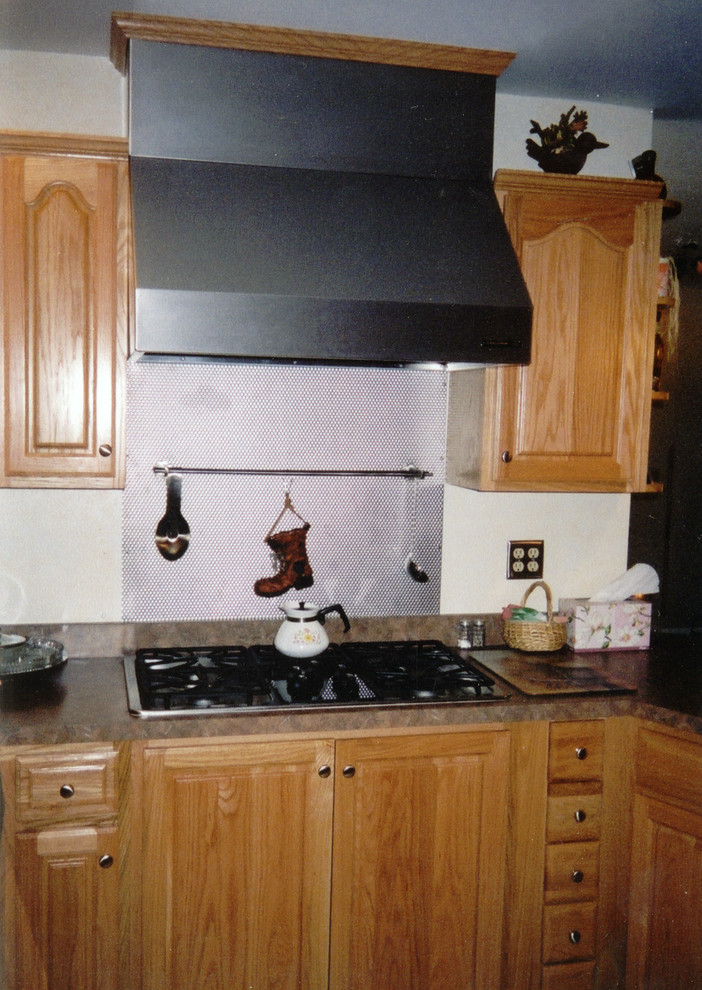 This is an example of a mid-sized traditional u-shaped kitchen in Other with a double-bowl sink, raised-panel cabinets, light wood cabinets, laminate benchtops, brown splashback, stainless steel appliances, ceramic floors, a peninsula, grey floor and brown benchtop.